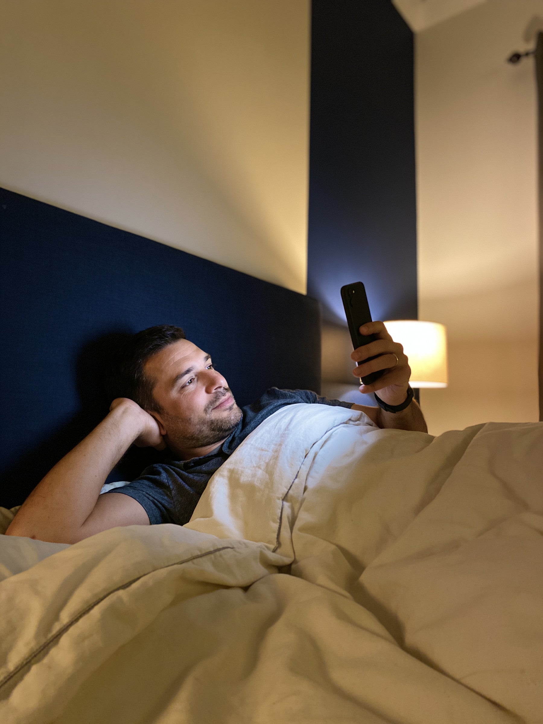 A father in bed at night glancing at his phone